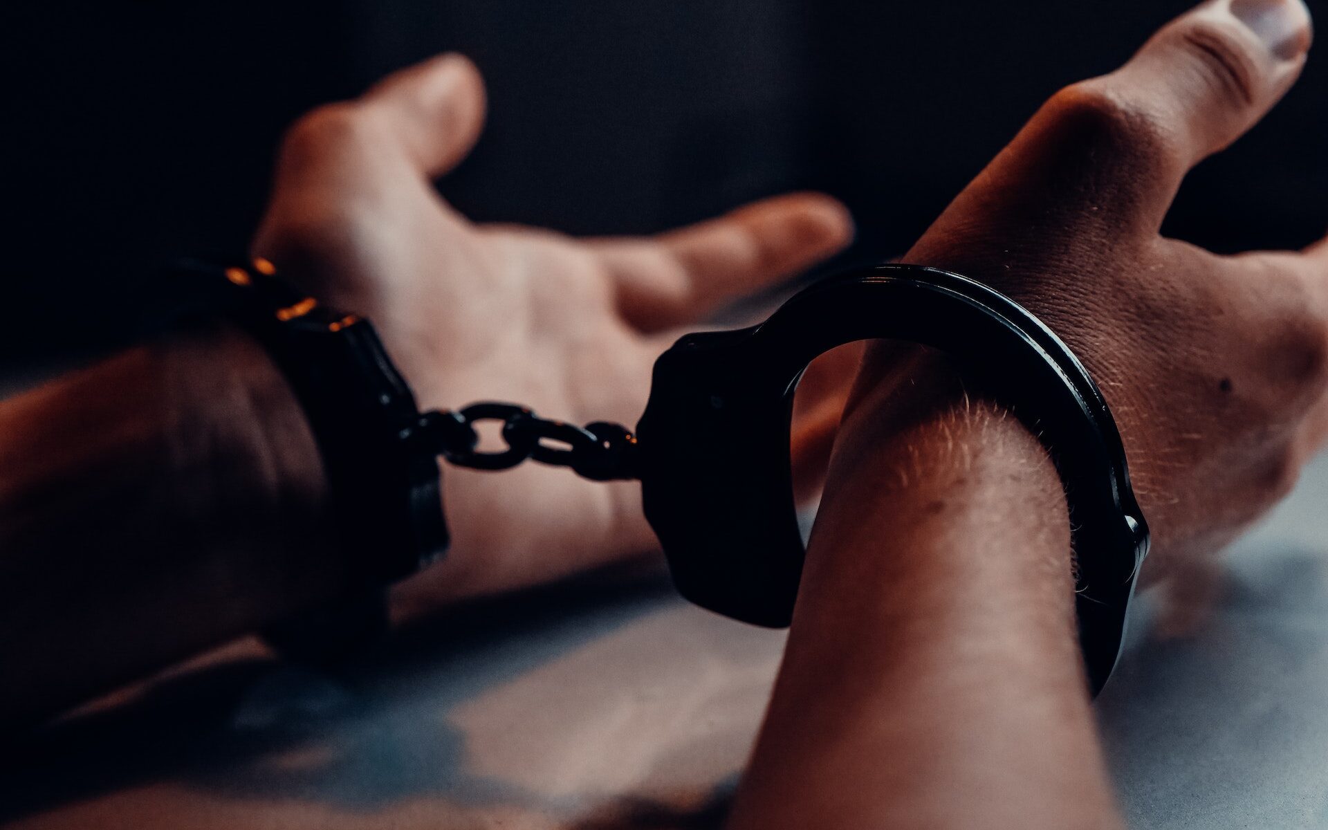 Caucasian male hands handcuffed on table