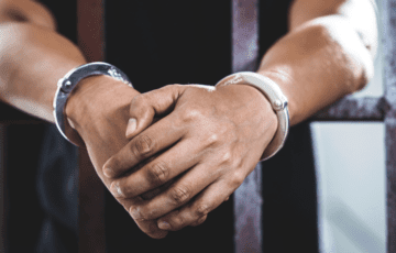 Person in handcuffs behind bars