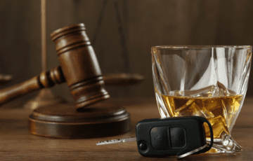 Courtroom gavel with brown alcohol in glass with car keys