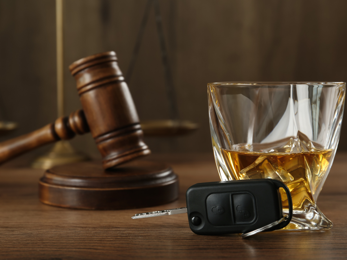 Courtroom gavel with brown alcohol in glass with car keys