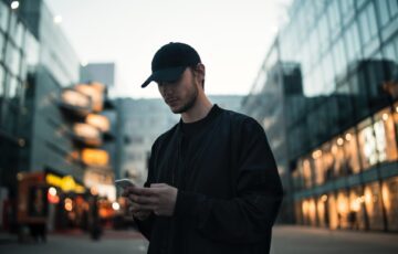 young man in black clothing using cell phone outside
