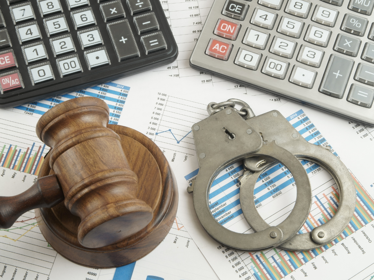 Gavel and Handcuffs next to calculators and financial documents