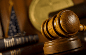 Wooden gavel on desk with flag behind it