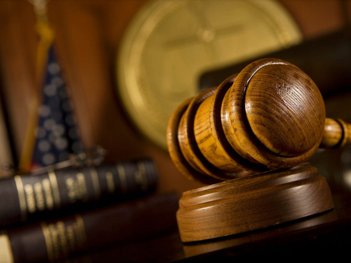 Wooden gavel on desk with flag behind it