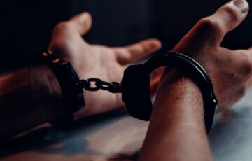 Caucasian male hands handcuffed on table