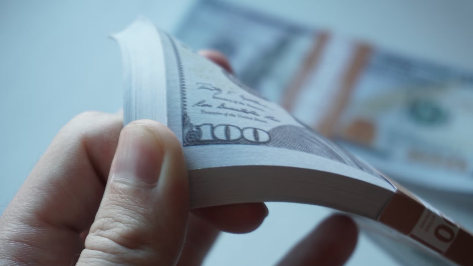 person holding a stack of 100 dollar bills