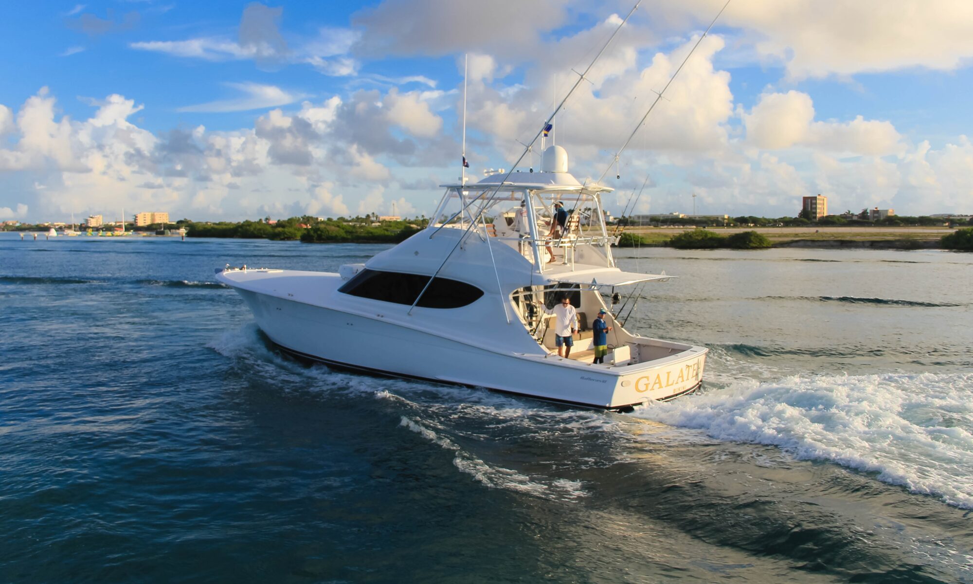 white yacht in the water with people fishing off the back