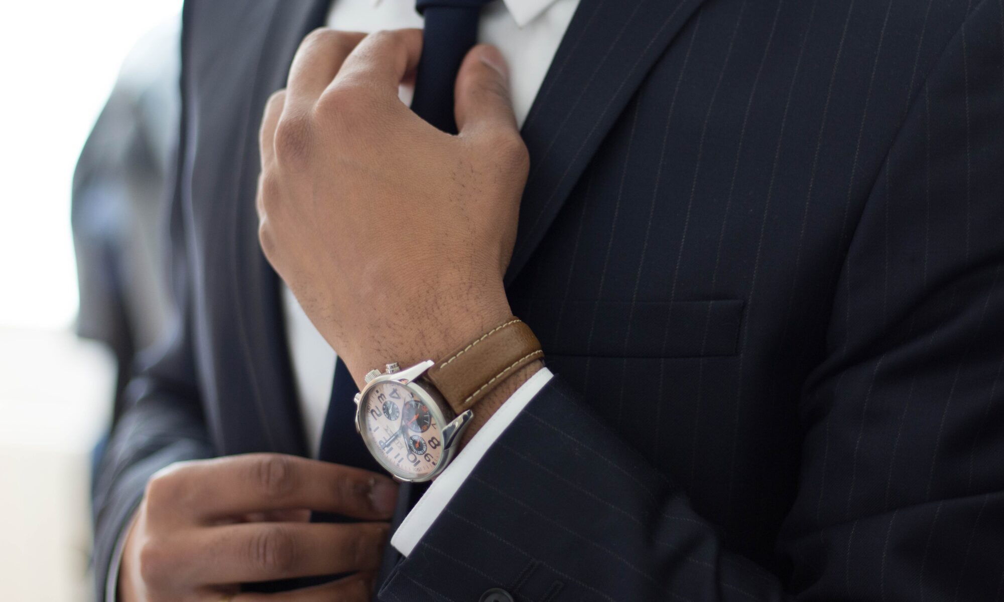 man in suit with hand on tie