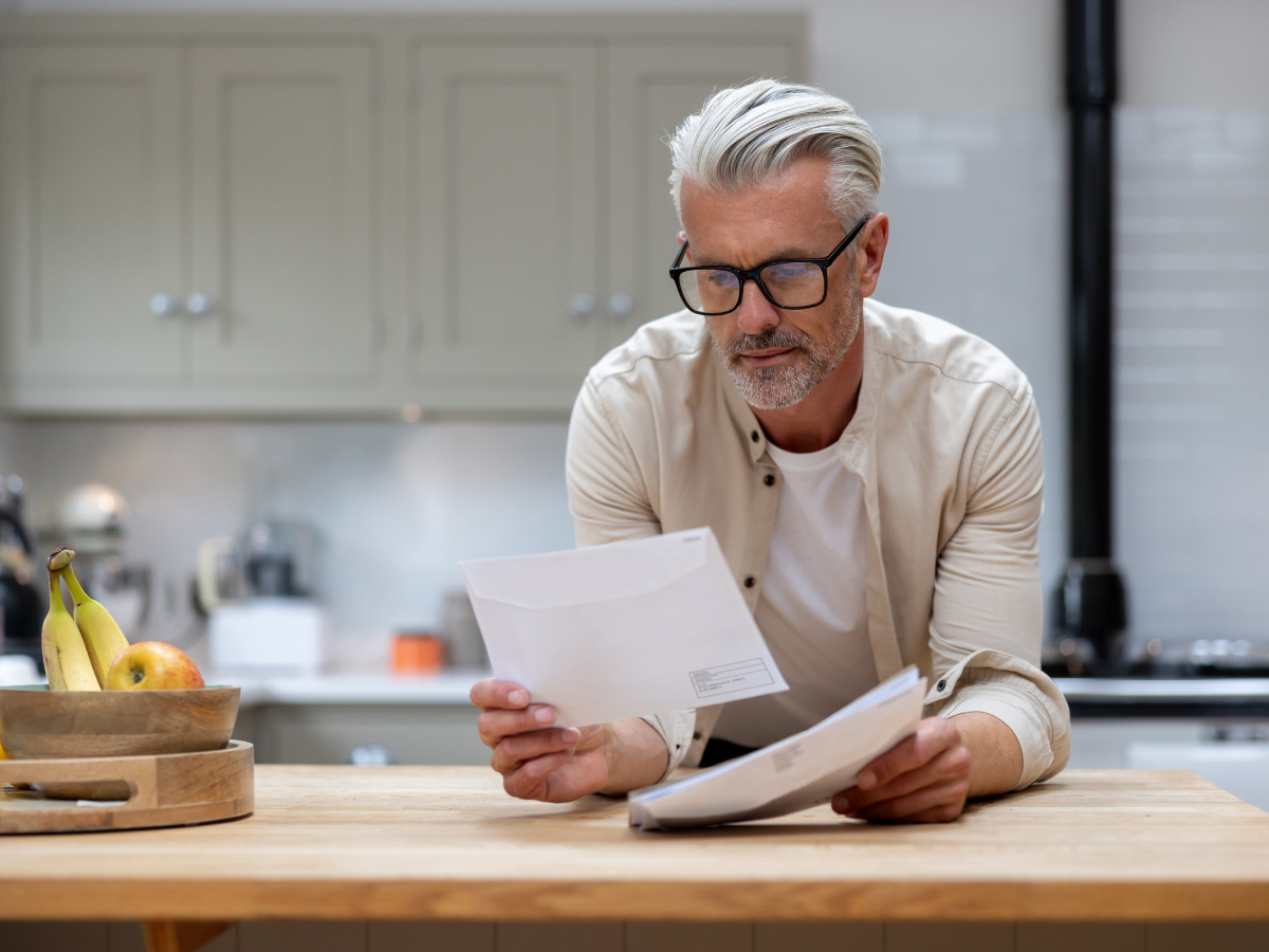man with glasses reading target letter at kitchen counter