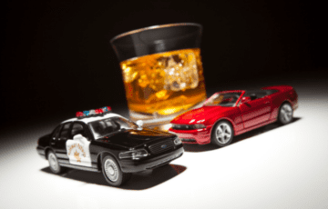 toy cars in front of glass of alcohol