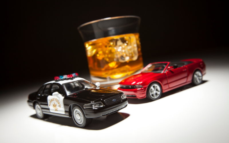 toy cars in front of glass of alcohol