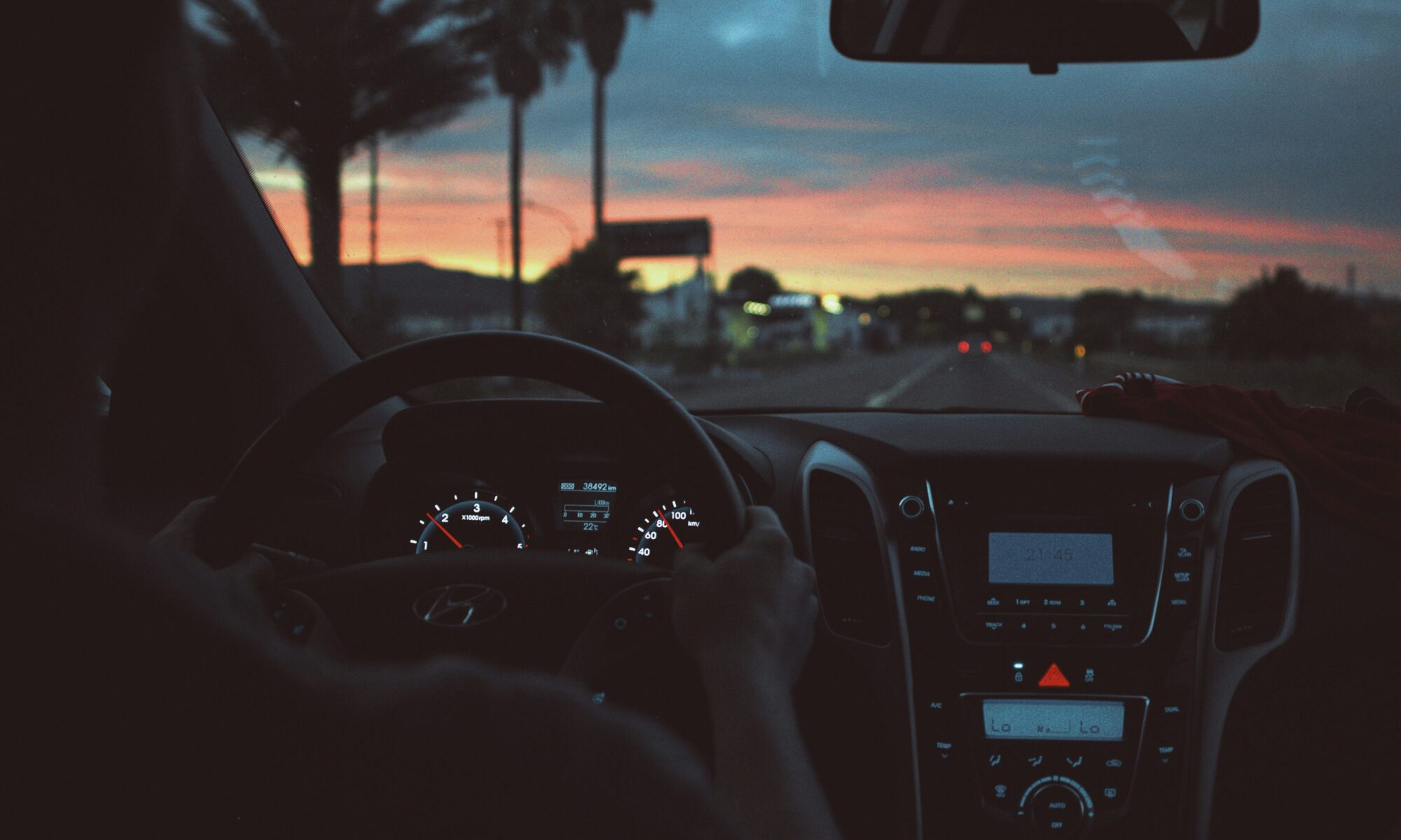 person driving car at night at sunset