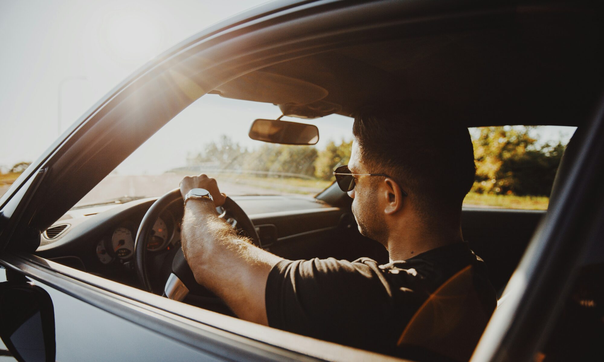 man driving a car during the day